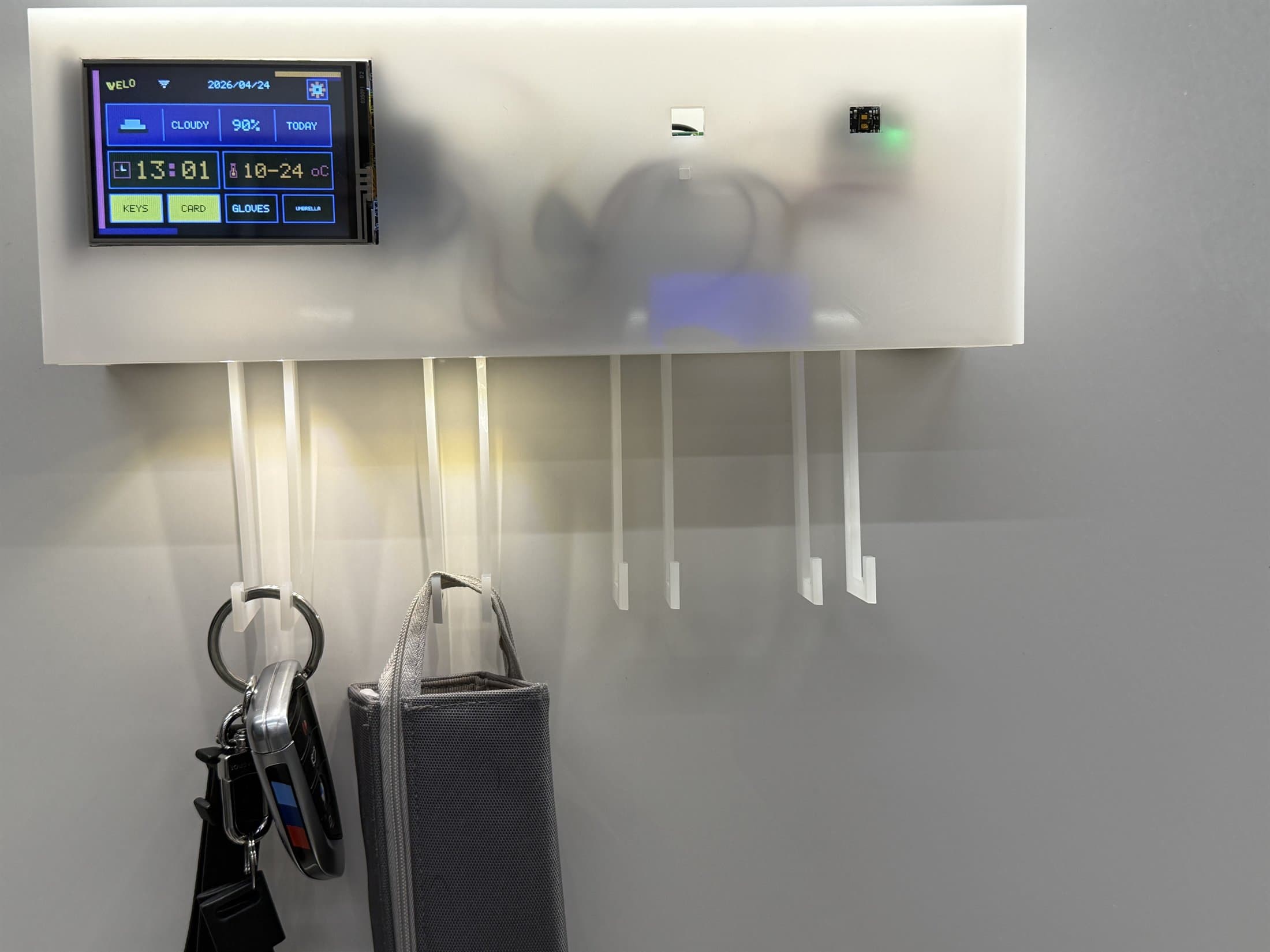 Velo installed on a whiteboard with keys and a small bag hanging below.