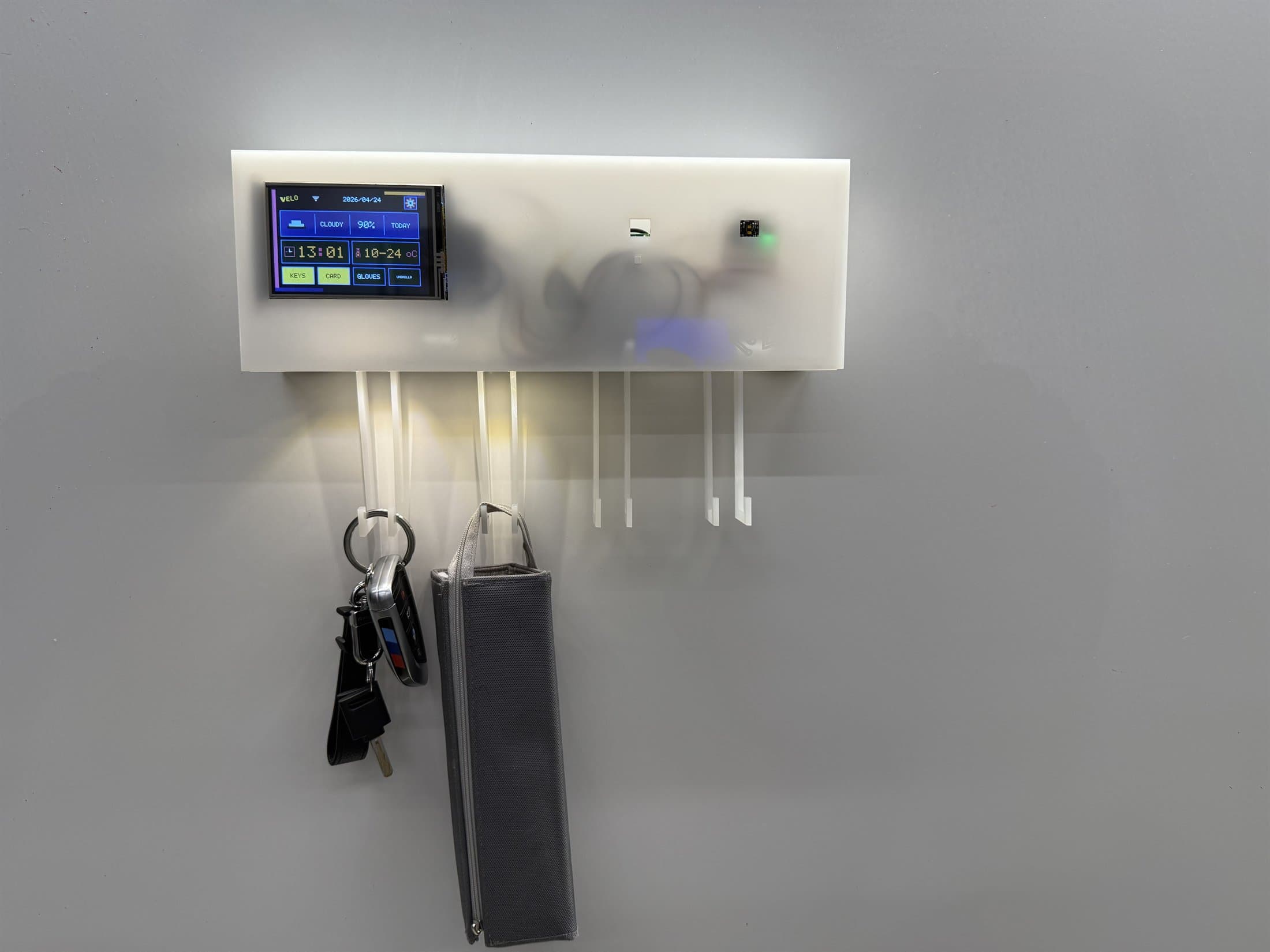 Velo installed on a whiteboard with keys and a small bag hanging from the hooks.